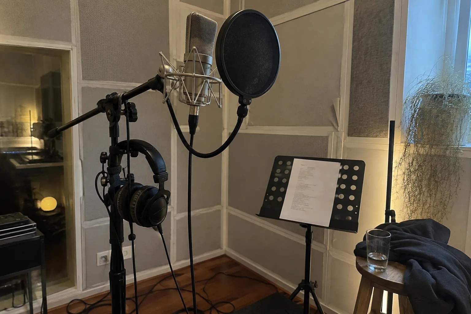 Gesangsmikrofon mit Popschutz und Kopfhörern in der Aufnahmeecke eines Studios