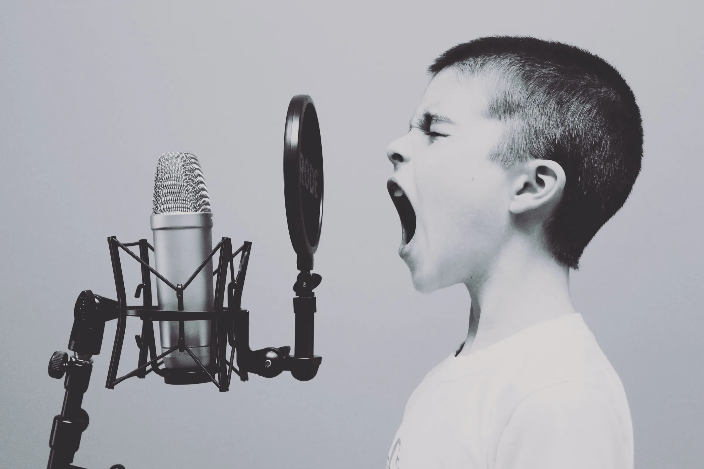 Kind singt leidenschaftlich in ein Mikrofon, symbolisiert klare Vorstellungen und Ziele bei der Zusammenarbeit mit einem Musikproduzenten in Zürich.